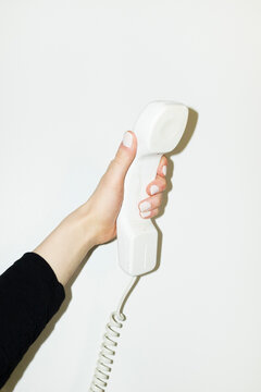 Hand holding white landline phone with curvy wire with flashlight