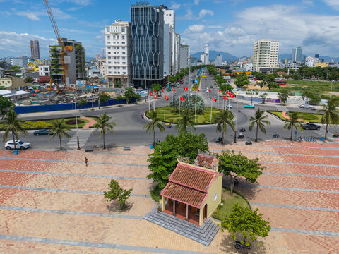 Small historic temple on paved steps alongside a busy city esplanade