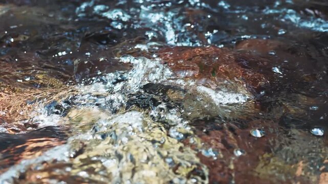 Cool summer river water flowing over rocks in slow motion