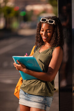 Teen girl writing outside with school folder