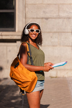 Smiling teenager with backpack and headphones outside