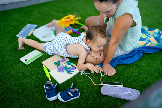 Mother and child playing with modeling clay on grass