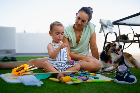 Mother and child playing outdoors with dog and toys