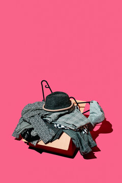 a box overflows with monochrome clothes beneath wide pink space
