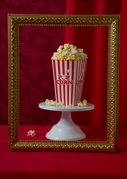 Popcorn in Striped Container Framed Against a Red Background