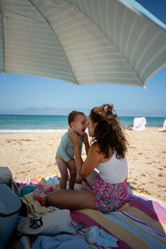 Mother applying sun protection to toddler at beach