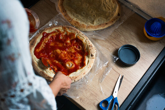 Spreading Tomato Sauce on Homemade Pizza Dough