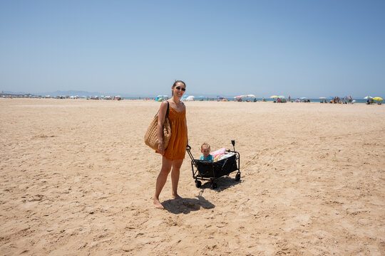 Woman with baby wagon on sunny beach vacation