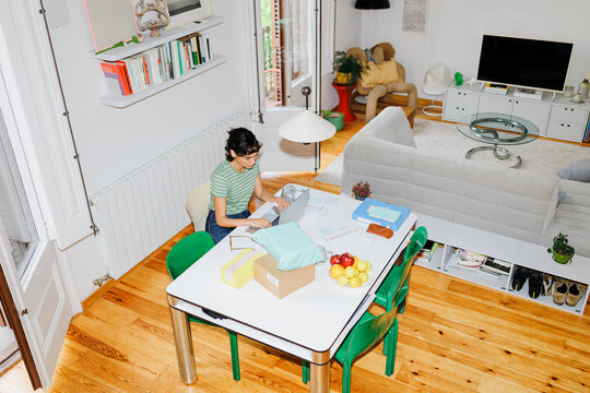 Woman working on laptop managing home business orders ugc
