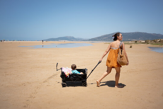 mother pulling child in beach cart 
