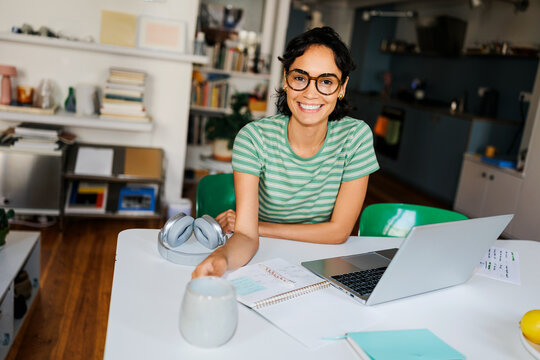 Woman working remotely from home smiling at camera ugc