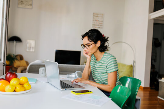 Woman working remotely using laptop at home ugc