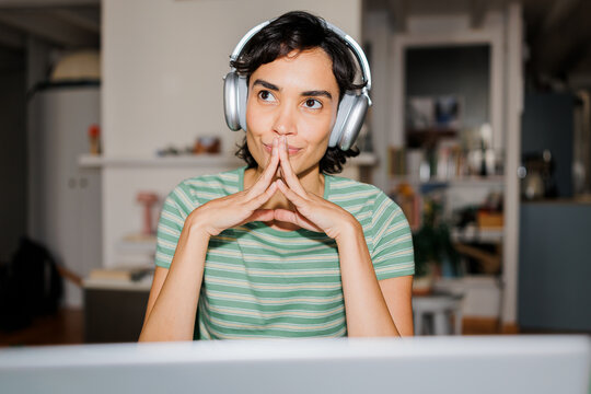 Woman wearing headphones thinking creating strategy at home ugc