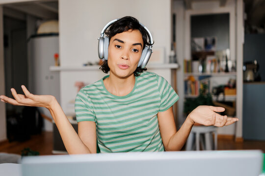Woman wearing headphones making gesture during video call ugc