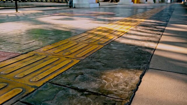 Static low angle shot of tactile paving tiles and yellow guide blocks on a pedestrian walkway outdoors in the historic old town district of Gresik, Indonesia.