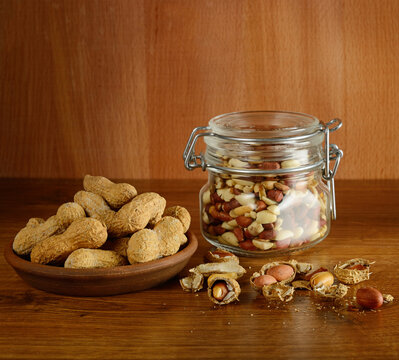 Roasted Groundnuts in Jar with Cracked Shells on Wooden Table