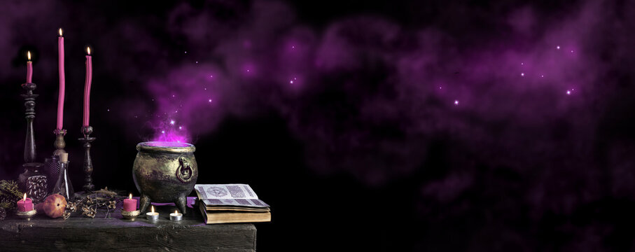 Halloween background with copy space. Dark witch cauldron with a magic witch's potion, spell book. Witchcraft paraphernalia and accessories among candles on a table