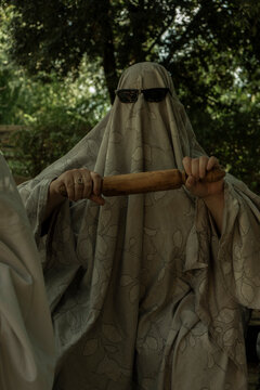 Person in Ghost Costume Holding Rolling Pin Outdoors