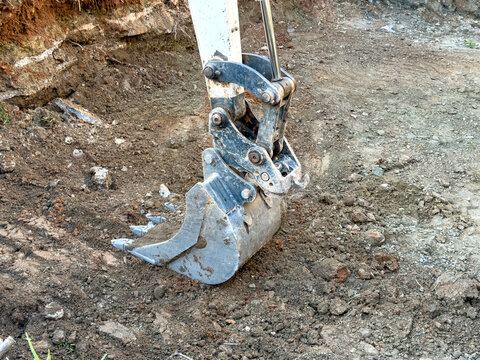 Hydraulic excavator bucket resting on disturbed soil at an active construction site