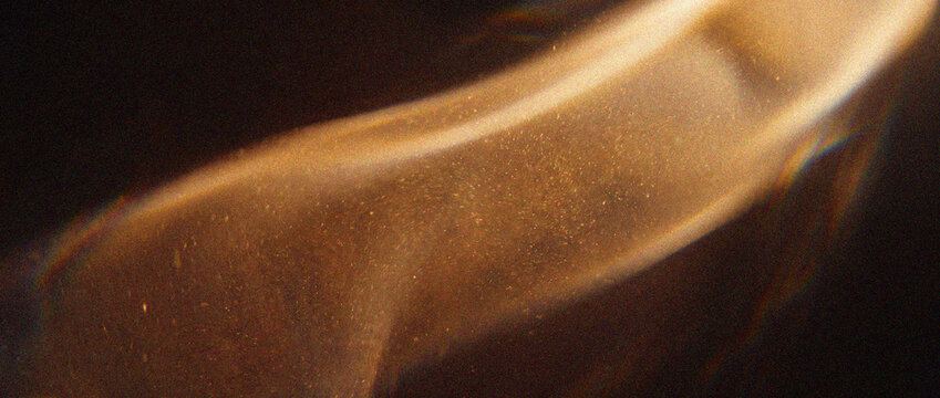 Light leak overlay with warm golden dust particles creates an atmospheric prism flare photo background on dark backdrop, perfect for creative photo editing and cinematic overlays