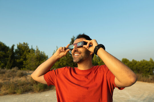 Man smiling while watching solar eclipse with protective glasses