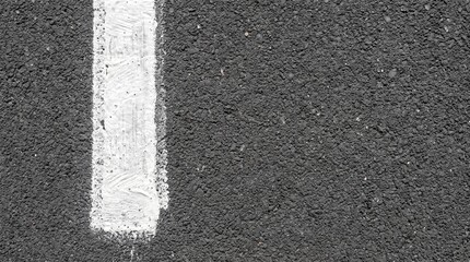 Fototapeta premium Textured dark asphalt road surface with a bright white painted line marking