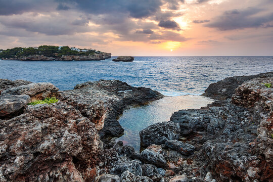 Warm sunset over rocky cove in Cala d'Or, Mallorca, Spain.