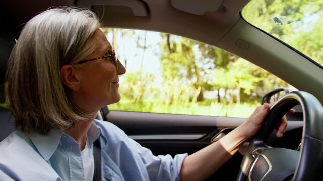 Smiling happy Caucasian senior old retired woman driving car sunny day enjoying test drive new rental auto buying enjoy traveling in automobile mature aged smile cheerful female granny inside vehicle