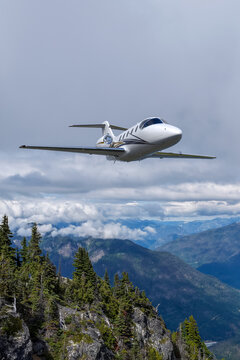 Private Business Jet Flying Above Mountain Clouds Over BC Canada Scenic Landscape