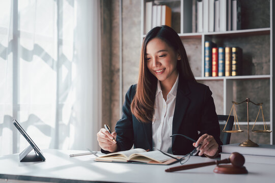 Asian Adult Woman Lawyer Working at Office Desk with Law Scale Justice Gavel Book and Tablet Computer Legal Services for Business