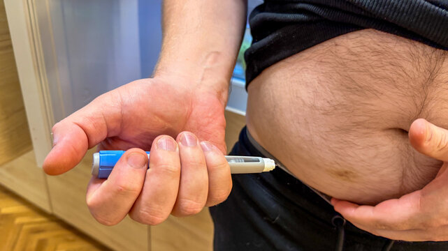 Adult man self GLP-1  Ozempic injecting into abdominal fat at home in natural light, candid instructional shot suitable for medical editorial, healthcare content and social media
