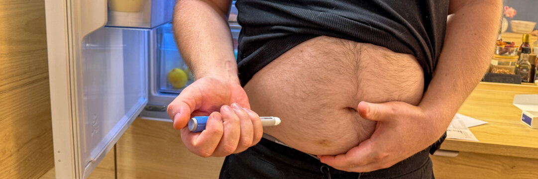 Close up of a man self GLP-1  Ozempic injecting medication into his abdomen at home in warm natural light suitable for medical editorial, patient education, healthcare marketing