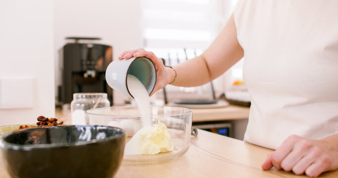 Pastry cooking. Homemade cuisine. Female baker hand pouring sugar cup in cream butter in bowl on kitchen table preparing sweet food.