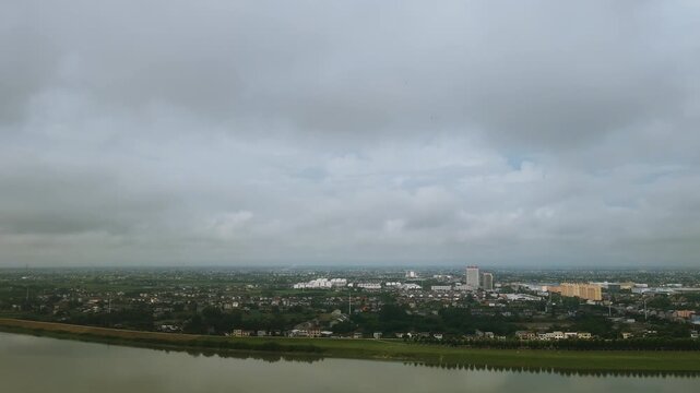 High angle time‑lapse of city river and urban area under cloudy moving sky