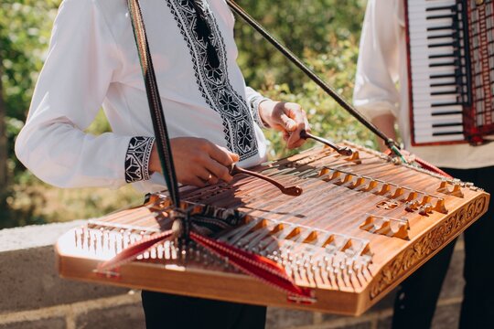Musician playing dulcimer instrument at outdoor folk concert