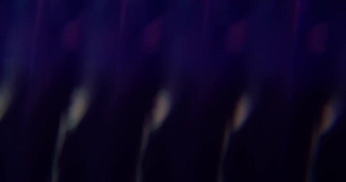 Defocused kaleidoscope flare. Colorful abstraction. Pink blue purple round optical glisten on luminous bokeh dark black background.