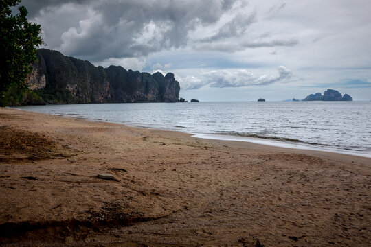 Ao Nang beach and tropical limestone cliffs landscape under cloudy sky in Krabi, Thailand