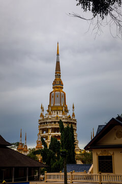 Golden pagoda spire of Wat Tham Suea Tiger Cave Temple under cloudy sky in Krabi, Thailand