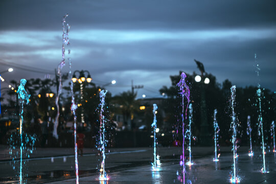 Illuminated water fountain splashes with colorful lights at night