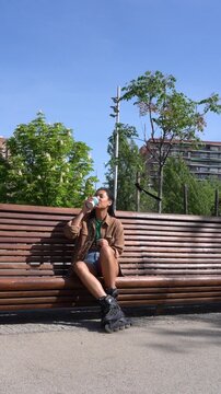 Woman with rollerblades drinking coffee in a sunny park