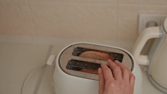 Closeup toast entering toaster warm kitchen counter, hand placing whole grain slice, kettle in background, soft ambient light, slow routine, music lover mood, textured crust, gentle domestic scene