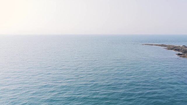 Aerial view of the tranquil blue sea meeting a rocky coastline at Anse du Croc, near Frehel in Brittany, France.