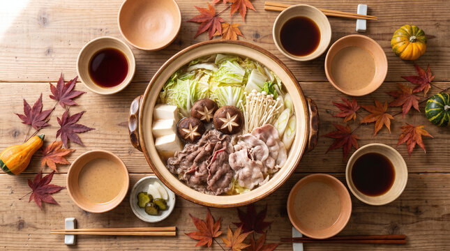 Overhead view of Japanese hot pot nabe dinner with vegetables and tofu on autumn table