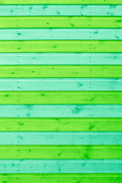 Wooden shiplap slats painted in green and blue stripes background backdrop. Painted garden shed in bright colours.