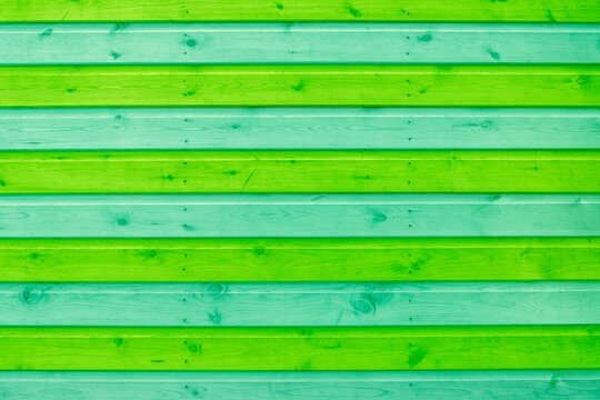 Wooden shiplap slats painted in green and blue stripes background backdrop. Painted garden shed in bright colours.