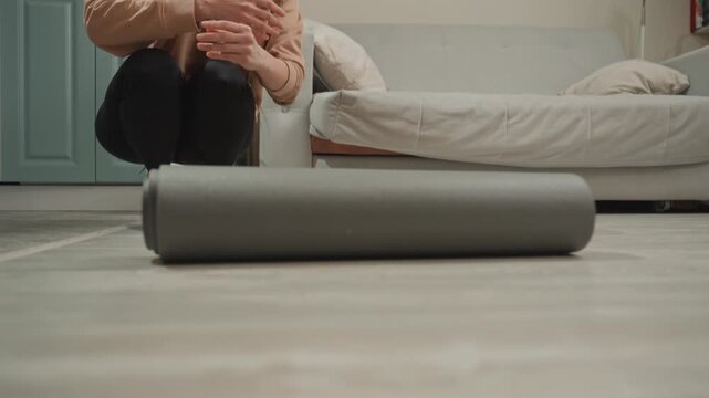 White woman unrolling yoga mat headphones around neck closeup on textured foam and floor, hands smoothing surface, minimalist apartment kitchen, focused warmup ritual before workout