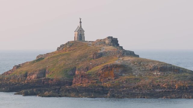 Wide shot of the Ilot Saint Michel, a small rocky islet off the coast of Erquy in Brittany, France, featuring the iconic Saint Michel chapel at its summit.
