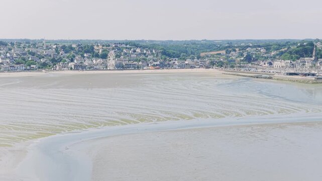 Aerial view of the coastal town of Binic in Brittany, France, with its sandy beach exposed at low tide.