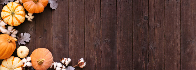 Obraz premium Fall corner border of pumpkins, leaves and natural decor over a rustic dark wood background. Top view with copy space.