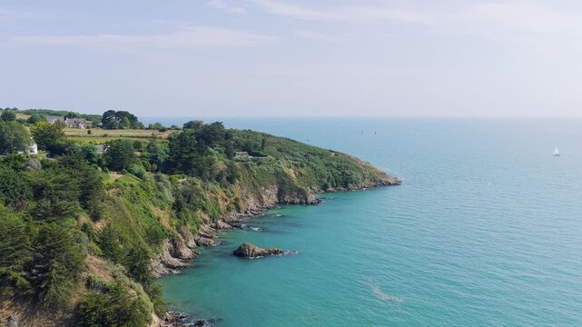 Aerial view of the dramatic green cliffs and rocky coastline of Binic, Brittany, France with the lush vegetation, scattered houses.